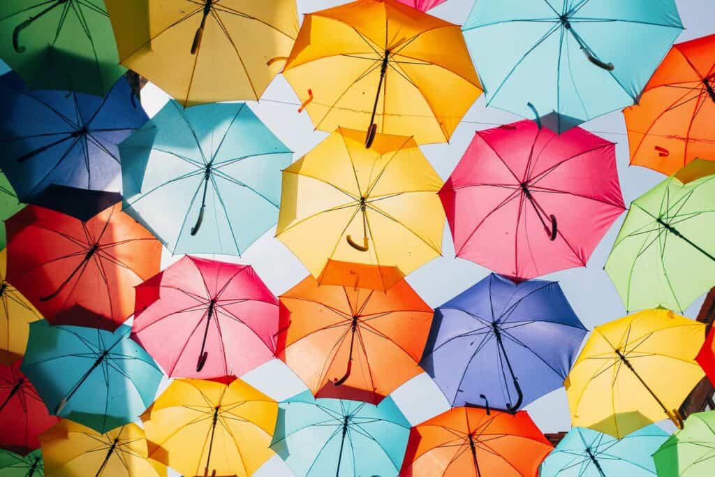 View from underneath many colorful umbrellas against a sunny blue sky