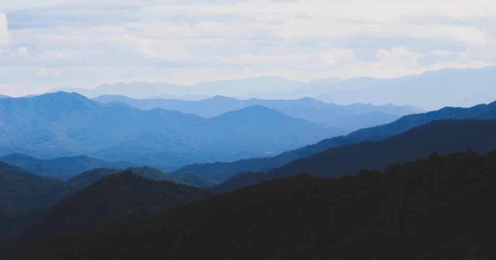View looking out at rolling hills that fade in color under a cloudy sky