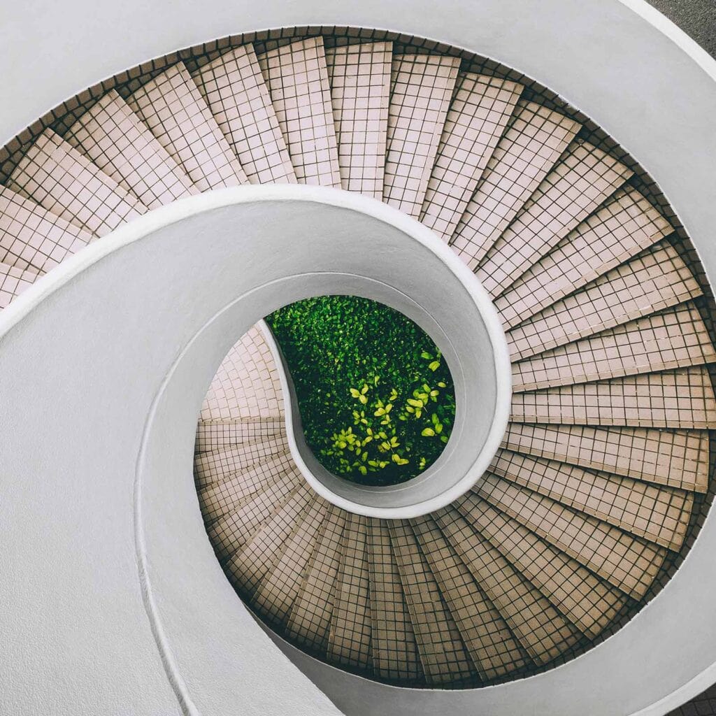 Birdseye view of a geometric spiral staircase represents the content lifecycle’s cyclical progress and strategic elevation.
