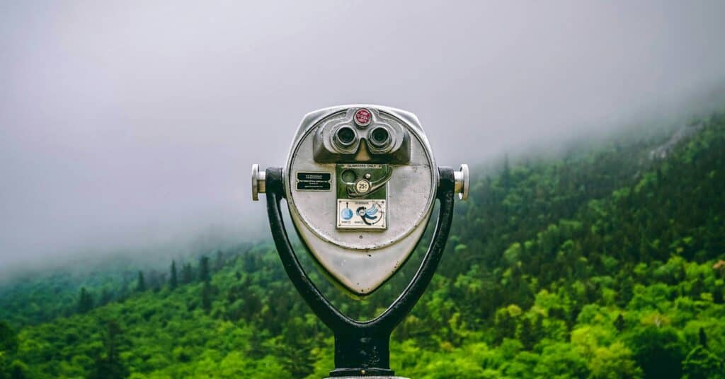 A viewfinder pointed at a misty mountain covered with green trees.
