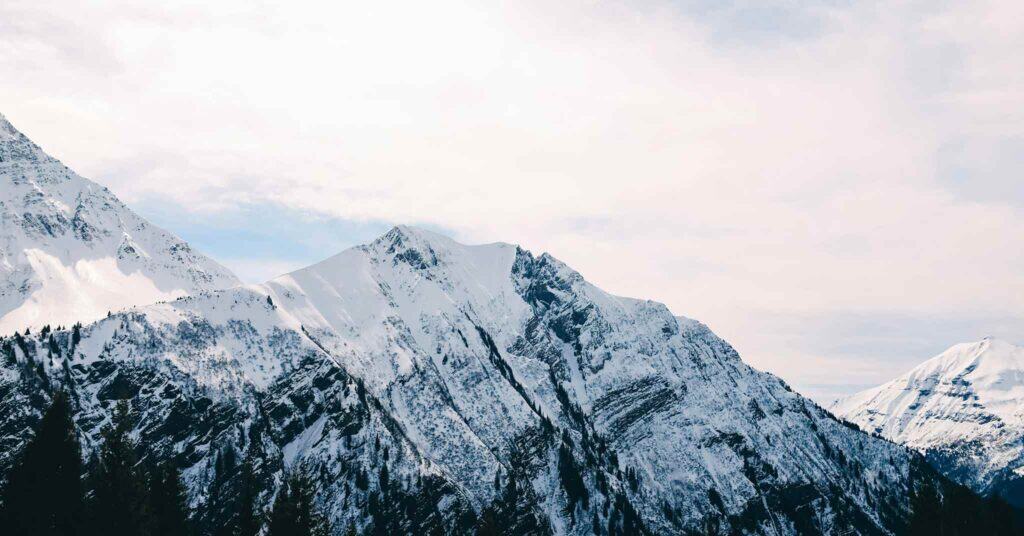 A snowy mountain peak in the foreground framed by two other mountains on each side.