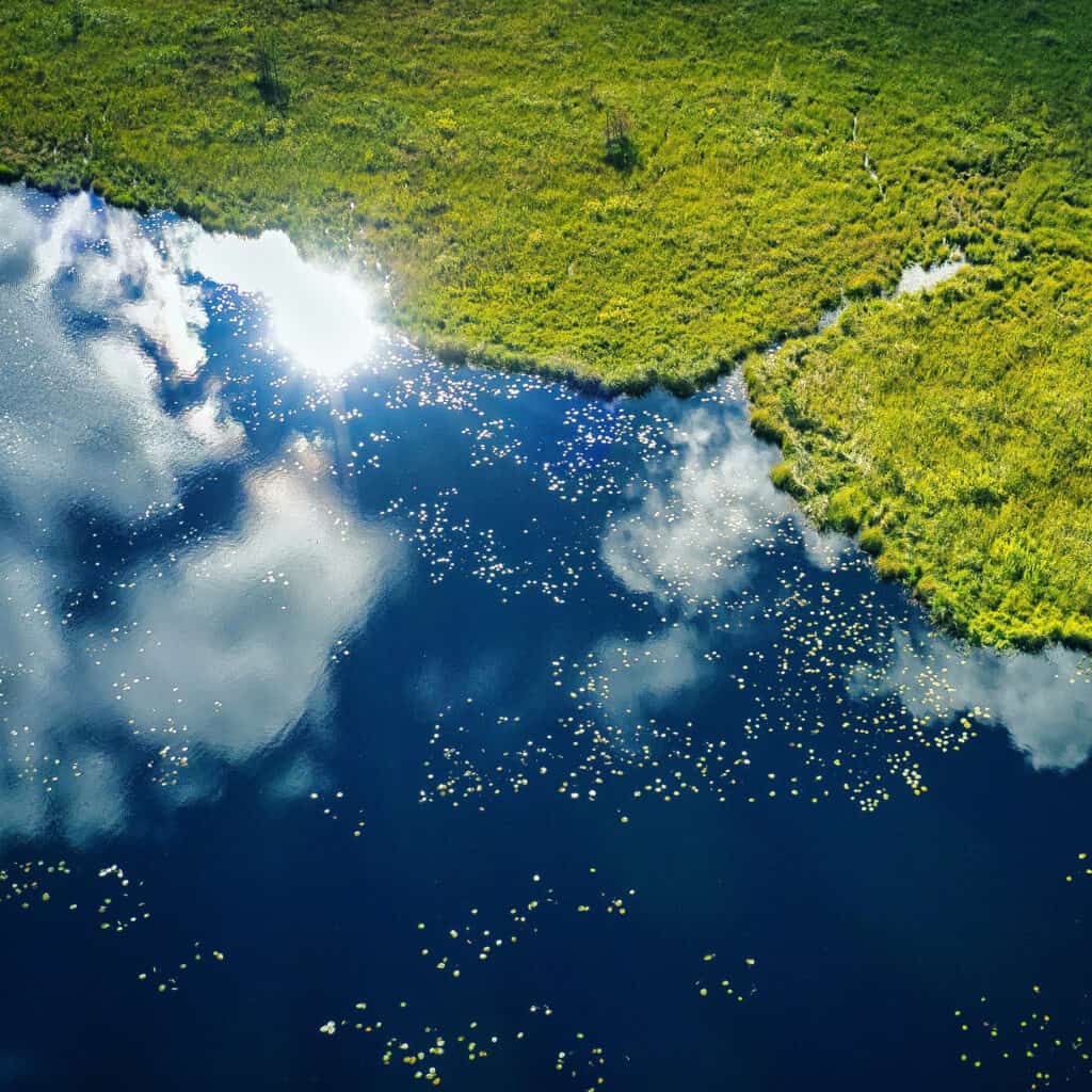 An aerial view of a marsh and water reflecting a cloudy sky.